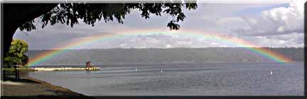 A panorama photograph of a low rainbow over Cayuga Lake.
